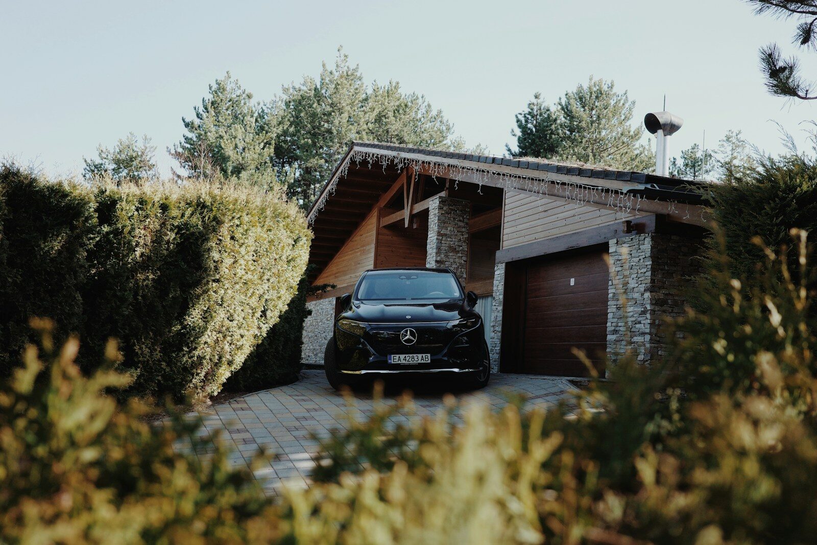 A black car parked in the driveway of a house.